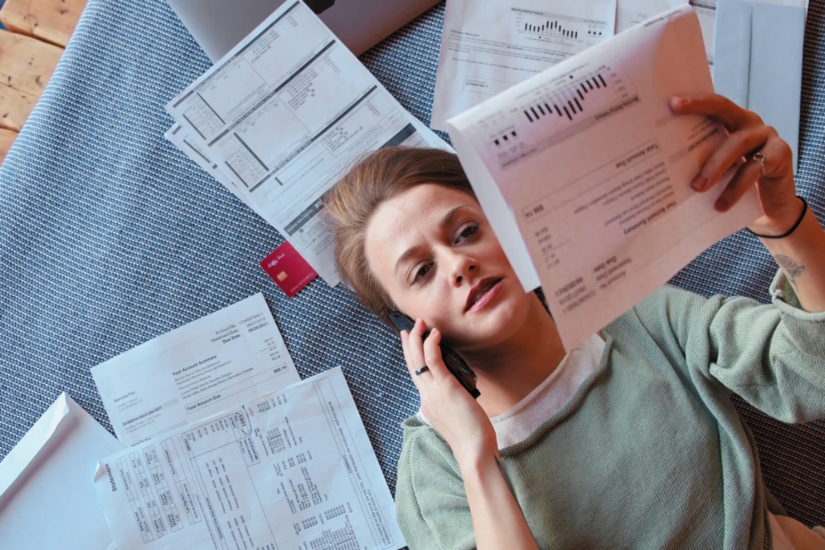 devojka gleda u račune za struju i priča na telefon