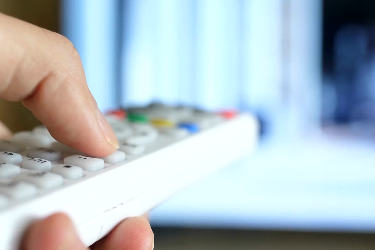 osoba drži daljinski u ruci bele boje