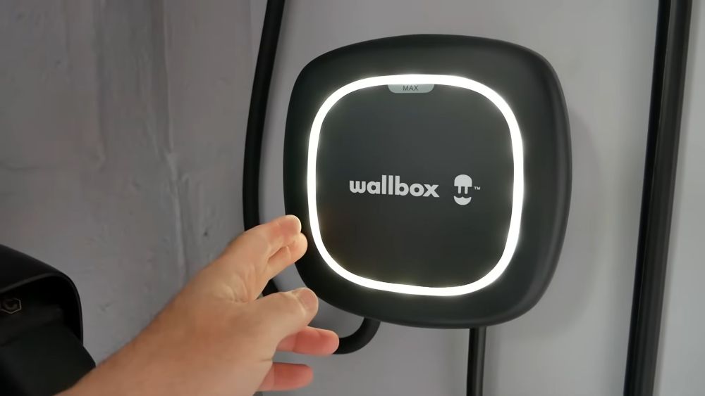 Wallbox Pulsar Max punjač montiran na zidu sa LED osvetljenjem i korisnikom koji podešava uređaj.