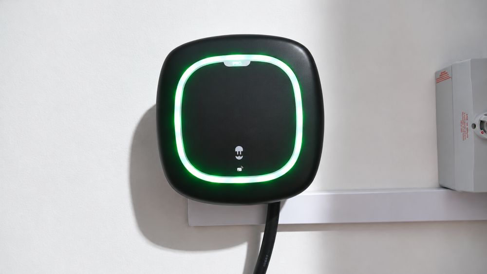 Wallbox Pulsar Pro EV punjač sa zelenim LED osvetljenjem montiran na zidu u poslovnom ili privatnom prostoru.