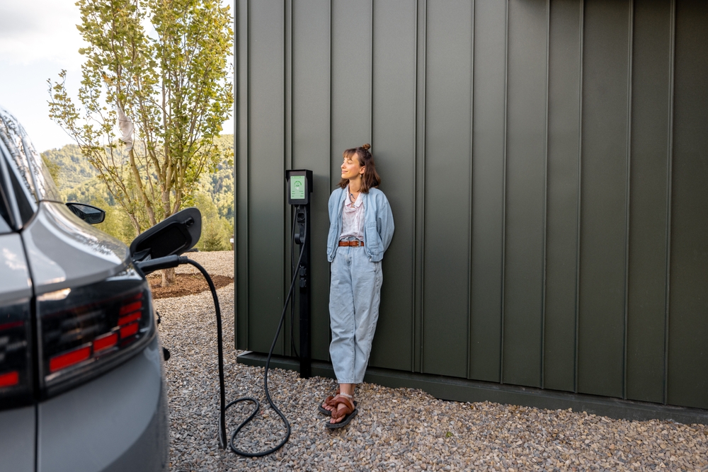 Električni automobil povezan na kućni wallbox punjač koji se nalazi na objektu.